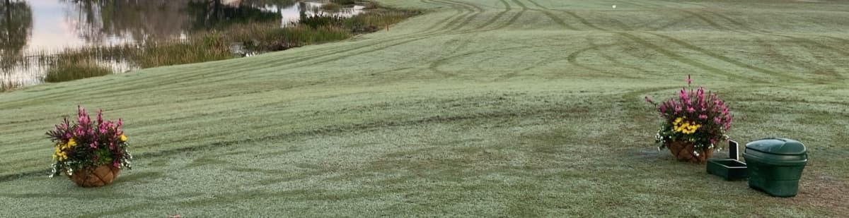 A tee box with flower planters looking down a fairway and lake at Cross Creek Country Club