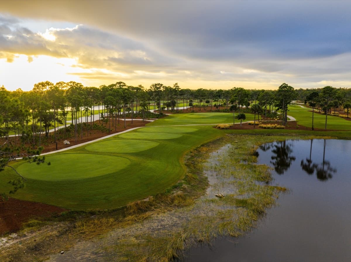 A sunset over a green, lake, and pine flatwoods at Saltleaf Golf Preserve